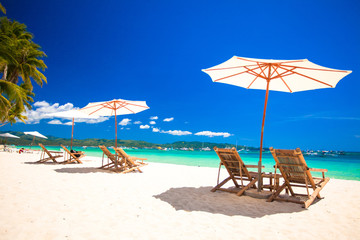 Beach chairs and umbrellas on exotic tropical white sandy beach