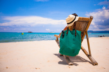 Young man relaxing in wooden chair on white sandy beach