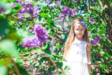 Adorable little girl in blossoming lilac flower garden