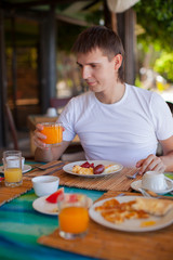 Young man having breakfast at outdoor cafe