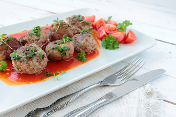 Meatballs with fresh herbs on a white plate