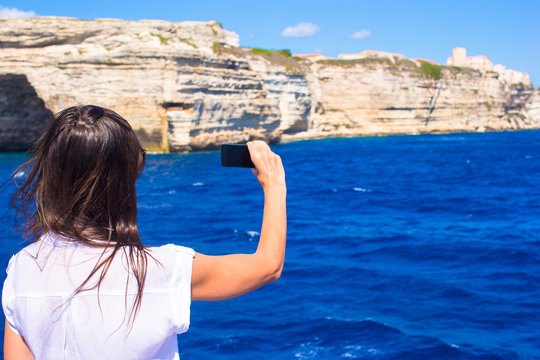 Girl taking pictures on a phone in Bonifacio, Corsica, France