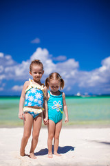 Adorable little girls have fun on white beach during vacation
