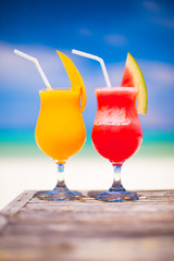 Two tasty fruits cocktails on background of turquoise sea