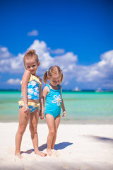 Naklejka premium Adorable little girls have fun on white beach during vacation