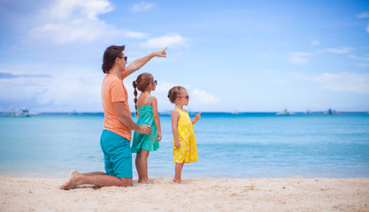 Little girls and young dad on white beach during summer vacation