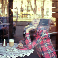 Young woman drinking coffee and use her smartphone sitting indoo