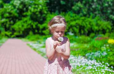 Little girl blowing a dandelion outdoor