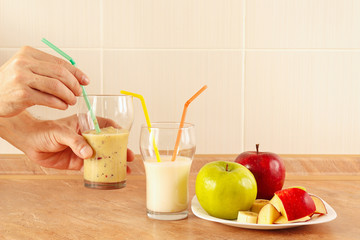 Hands chef offers a multyfruit smoothie in glasses