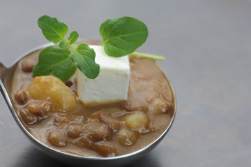 Ladle of lentil soup with feta cheese cubes and fresh oregano.
