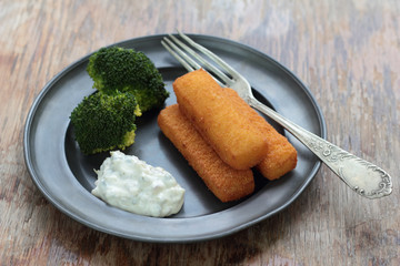 Fried fish fingers with broccoli and tartar sauce.
