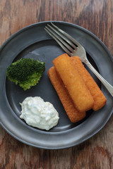 Fried fish fingers with broccoli and tartar sauce.