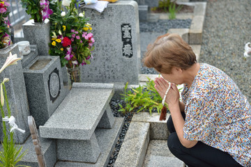 お墓で祈る女性