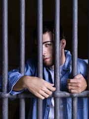 Imprisoned man, looking down, seized to a few bars