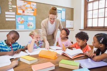 Pretty teacher helping pupils in classroom