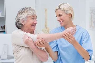 Obraz premium Happy nurse assisting patient in raising arm