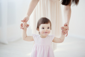 little girl first steps with the help of mom