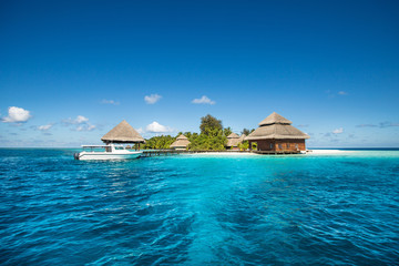 small tropical island with Beach Villas and speed boat - obrazy, fototapety, plakaty