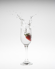 Strawberry falls deeply under water with a splash