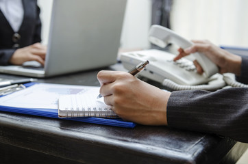 Business person dialing telephone in office