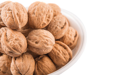 Walnuts in a white bowl over white background