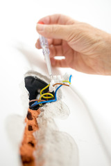 Hand of an electrician checking the presence of electrical curre