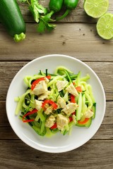 Healthy zucchini noodle dish with chicken on wood background