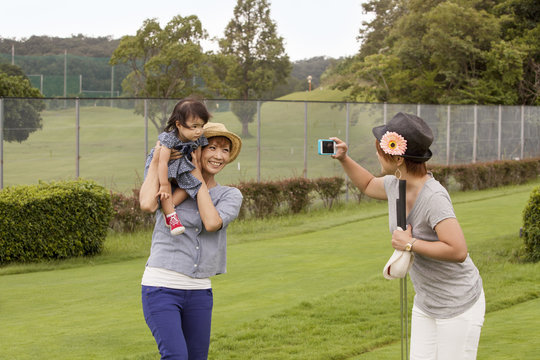 Family on a golf course. A woman using a camera. 