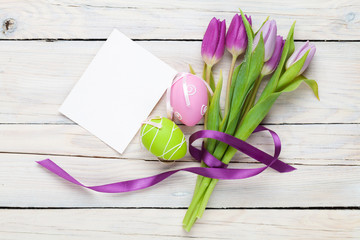 Fototapeta premium Purple tulip bouquet, easter eggs and blank greeting card