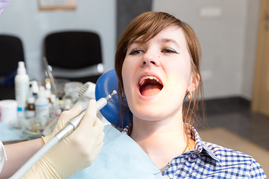 Drill in hand dentist and girl with mouth wide open