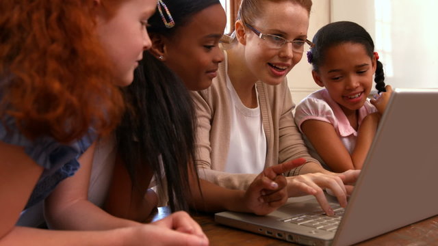 Teacher looking at laptop with pupils