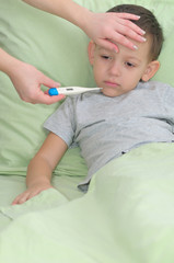 Mom measures the temperature of a patient boy