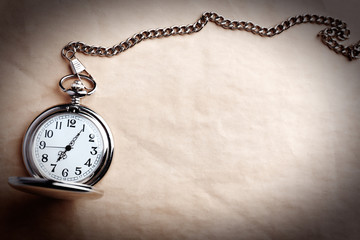 Silver pocket clock on old paper background