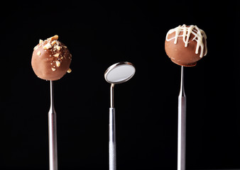 Dentist tools with sweets isolated on black