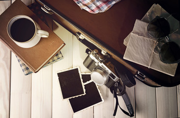 Vintage suitcase with books and camera on wooden background