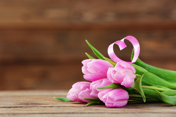 Beautiful pink tulips with decorative heart on wooden