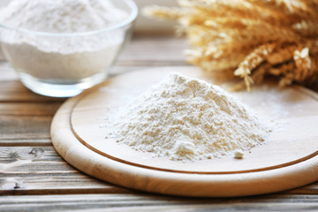 Pile of flour on cutting board with glass bowl, closeup