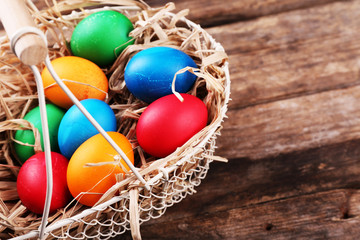 Easter eggs in basket on vintage wooden planks background