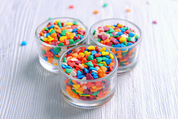 Colorful sprinkles in bowls on table close-up