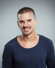 Portrait of smiling young man posing against gray background