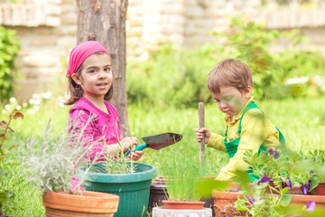 Two little kids planting flowers in the garden