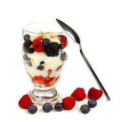 Mixed berry, granola and yogurt parfait with leaning spoon