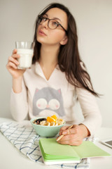 Woman making notes in notepad with glass of milk in hand
