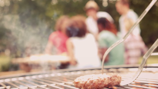 In slow motion burger on flaming barbecue in the park