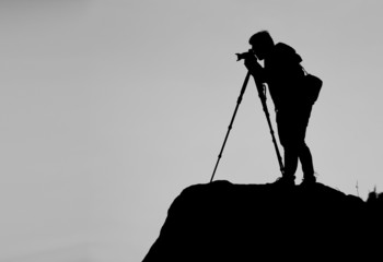 Silhouette of a photographer who shooting a sunset on the mounta