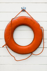 Orange ring lifesaver hanging on white wood background