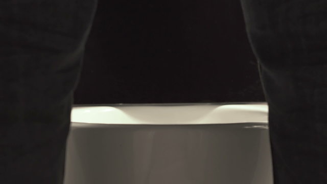 Slowly falling drops in the toilet between male legs