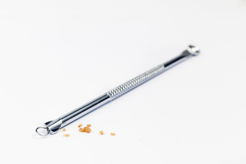 Closed up of pimple popping tool and the extracted blackheads