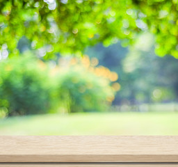Naklejka na ściany i meble Empty wood table over blurred trees with bokeh background