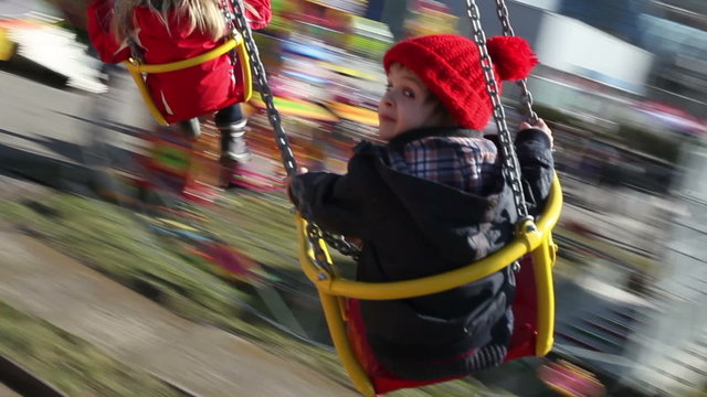 Adorable boy, going on a merry-go-round chain swing attraction